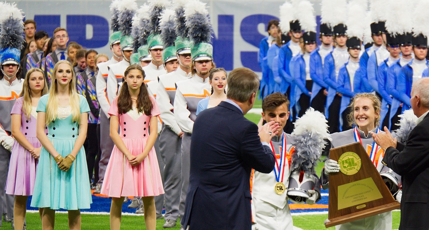 Drum majors Cameron Bussell and Maddie Tucker accept the first-place trophy and medals as fellow band mates wait anxiously to celebrate. [See much more of the prelim and finals performances.]